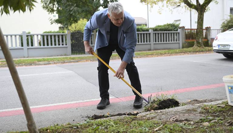 FOTO in VIDEO: Primc po vložitvi kandidature cestne odtoke čistil kar v obleki